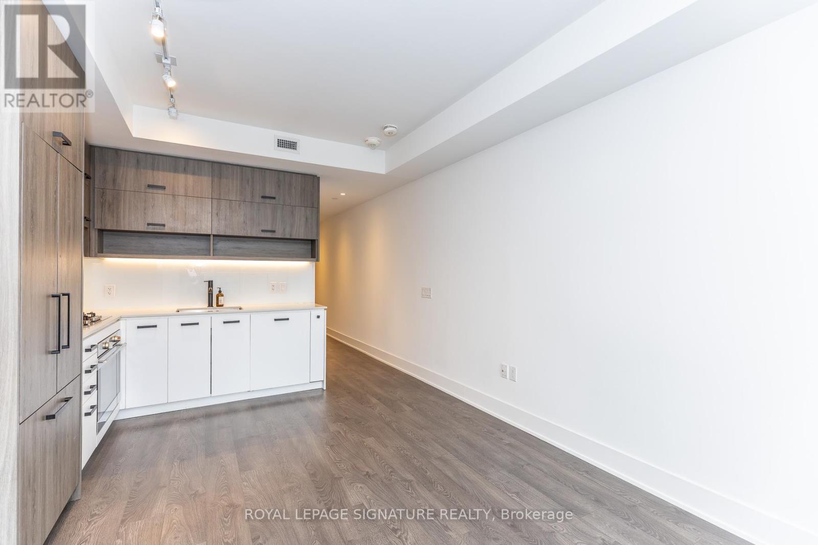 A spacious kitchen with white cabinets and a wooden floor.
