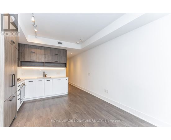 A spacious kitchen with white cabinets and a wooden floor.