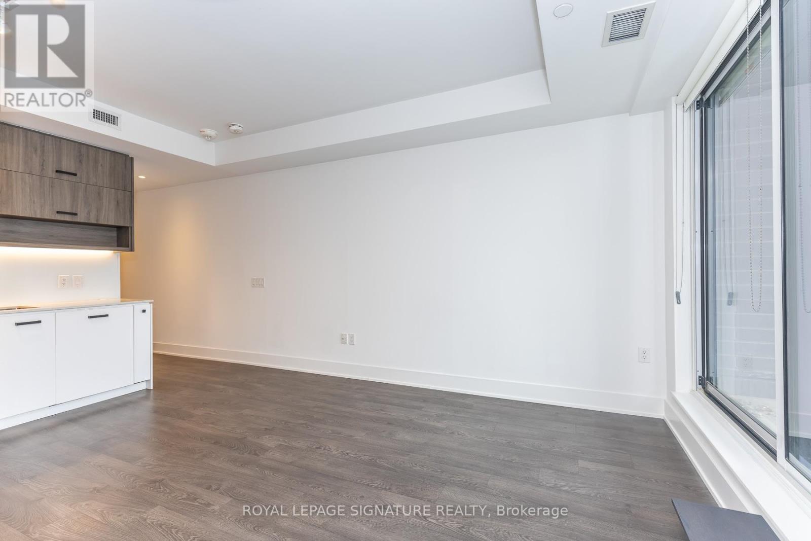 A spacious room with a wooden floor and white walls.