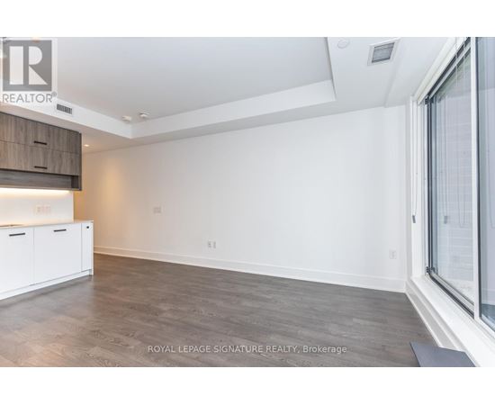 A spacious room with a wooden floor and white walls.