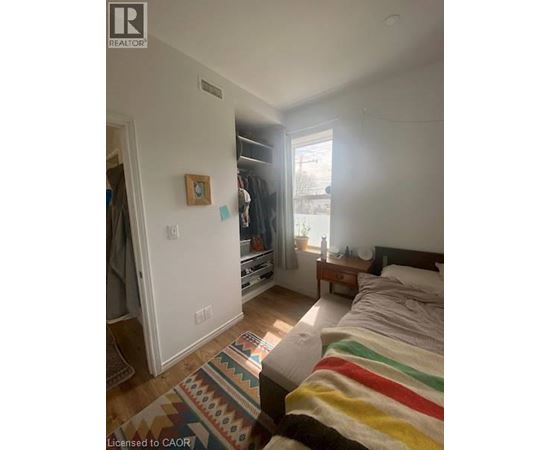 A bedroom with a bed, a rug, and a window.