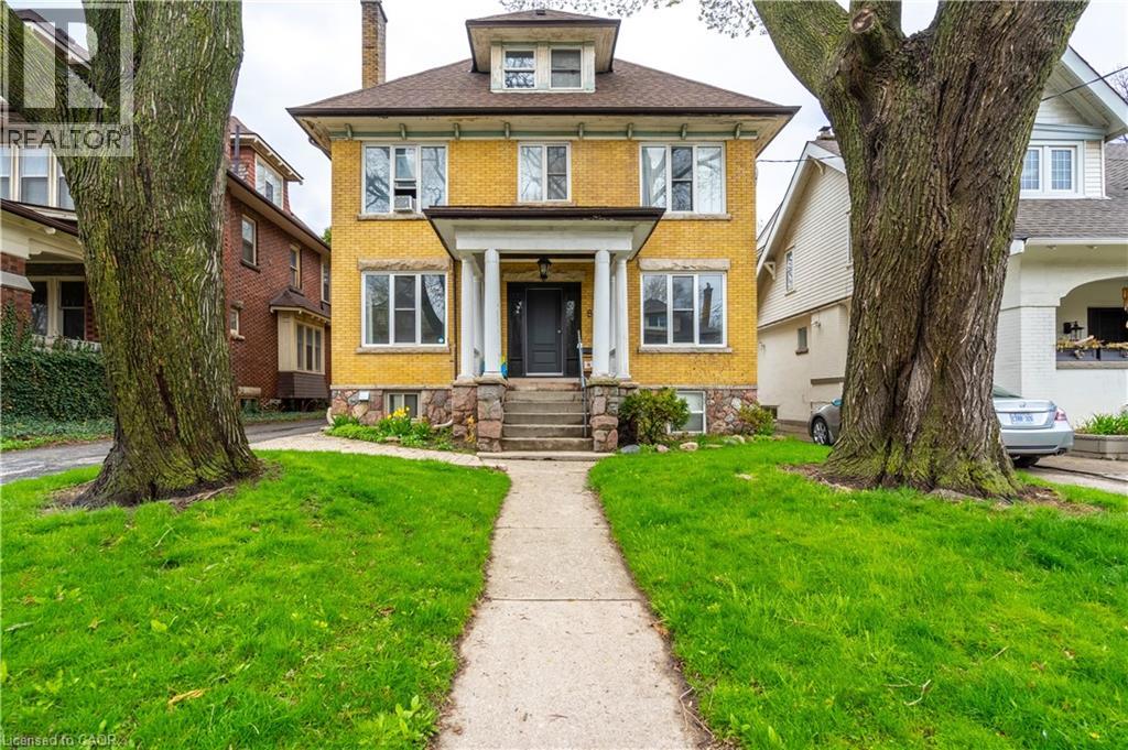 A yellow house with a black door and a stone step leading to it.