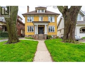 A yellow house with a black door and a stone step leading to it.