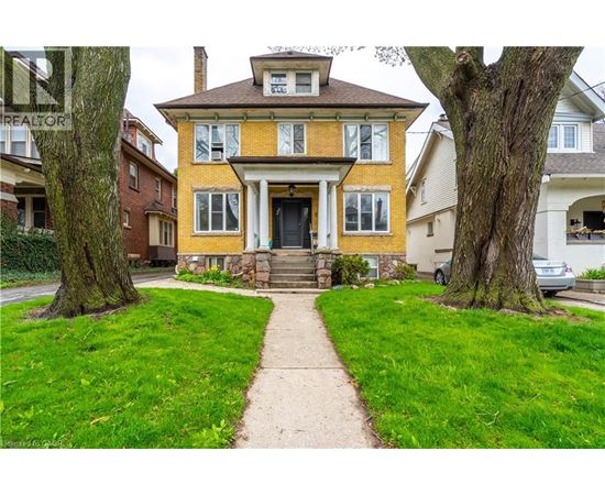 A yellow house with a black door and a stone step leading to it.