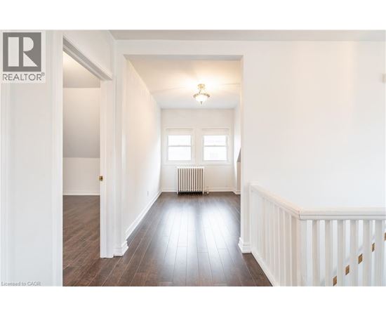A spacious room with wooden floors and white walls.