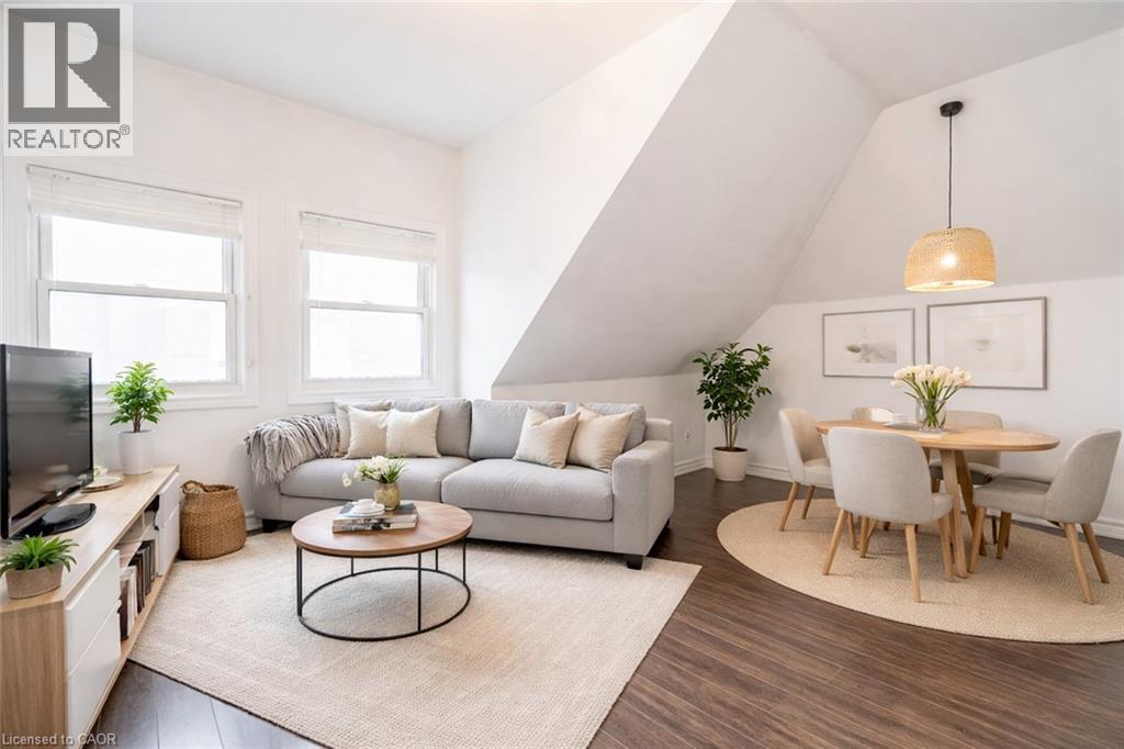 A living room with a grey sofa, a coffee table, a dining table with chairs, and a television.