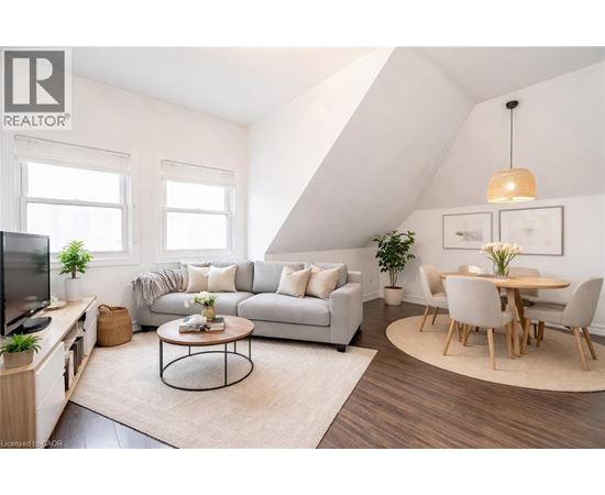 A living room with a grey sofa, a coffee table, a dining table with chairs, and a television.