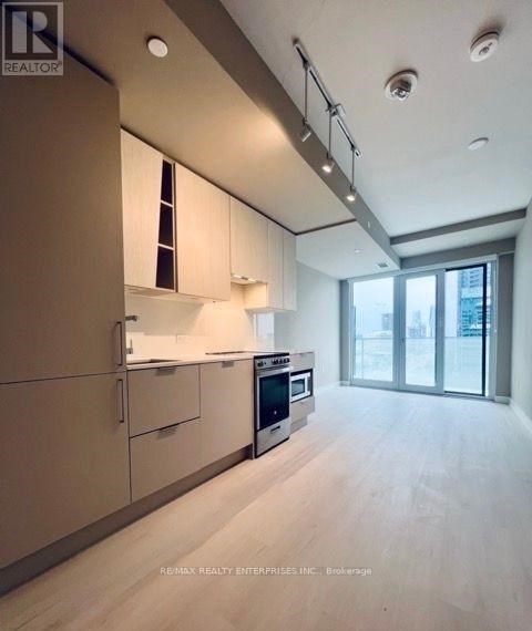 A modern kitchen with white cabinets and a wooden floor.