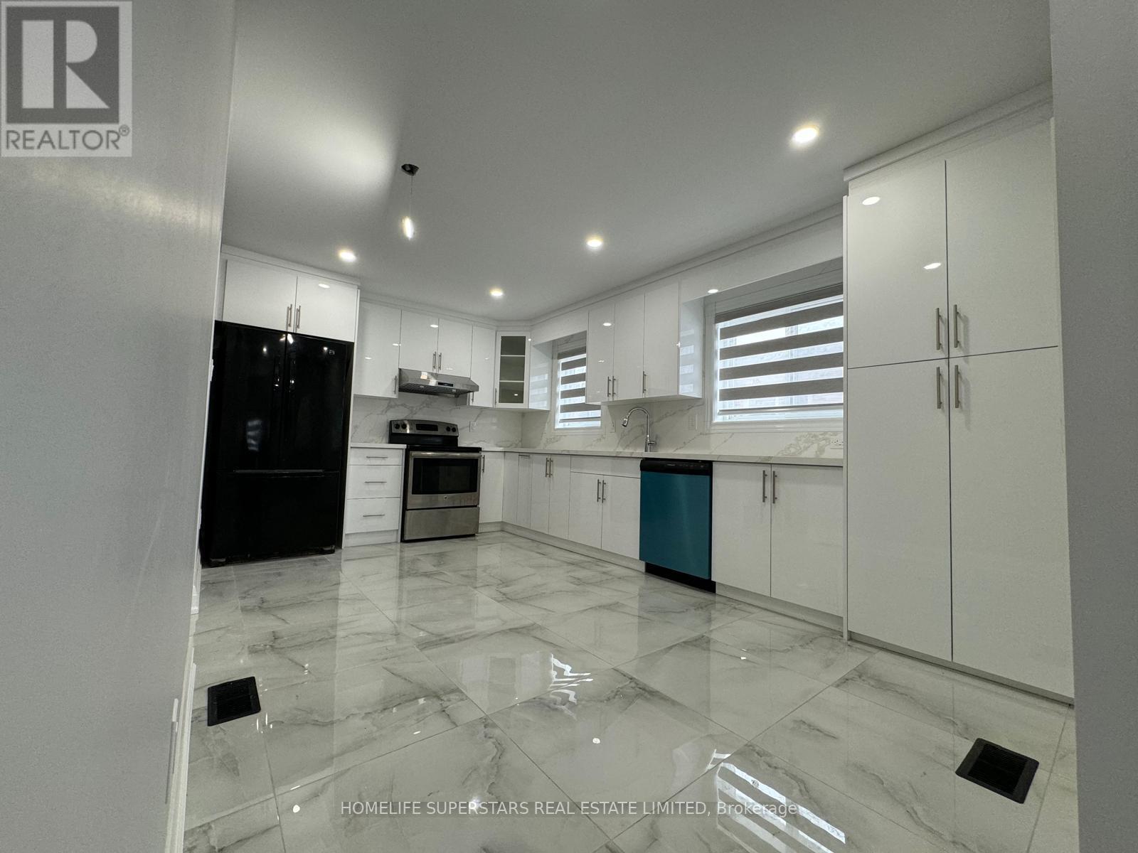 A spacious kitchen with marble flooring and white cabinetry.
