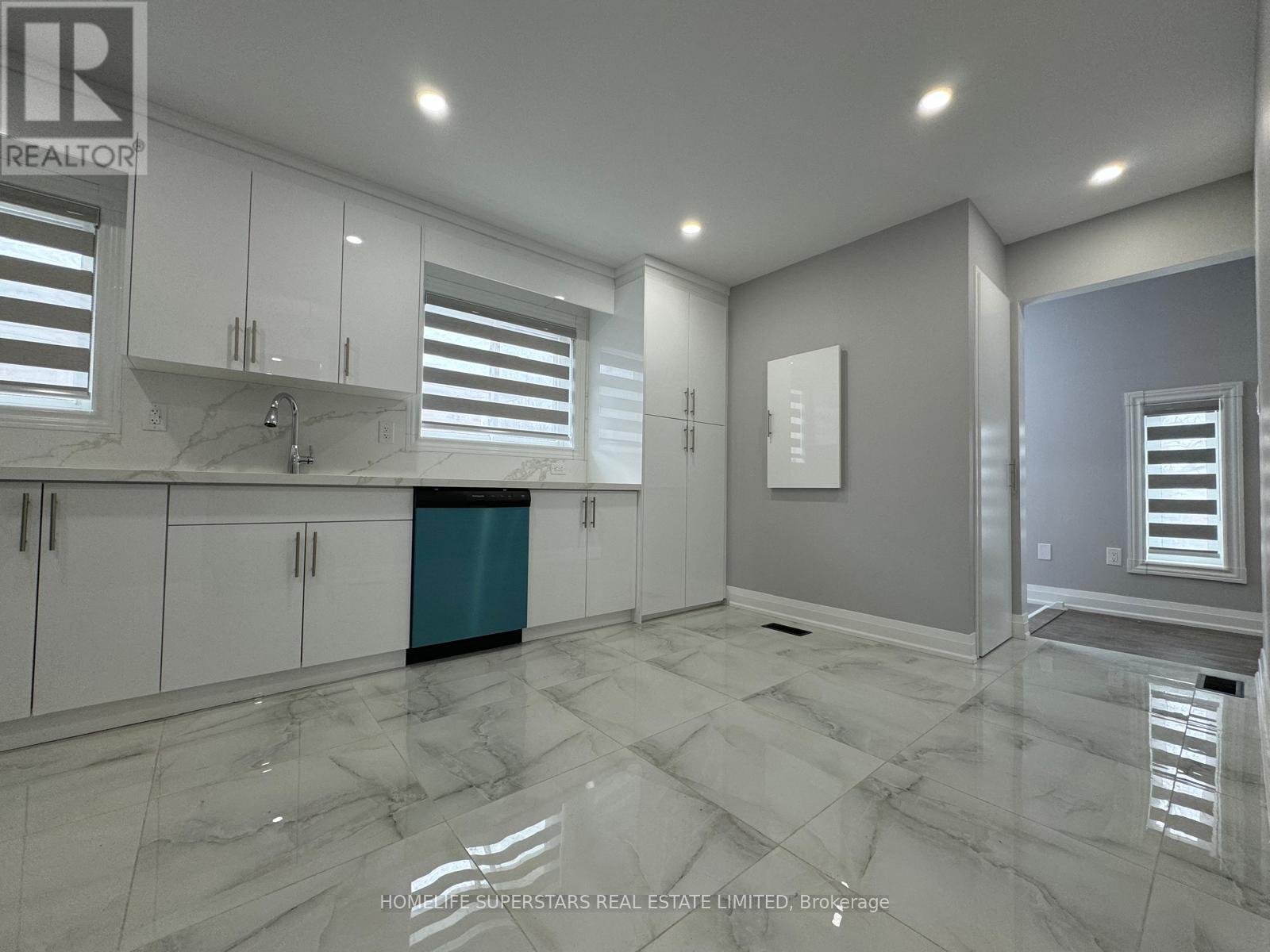 A modern kitchen with white cabinets and a marble floor.