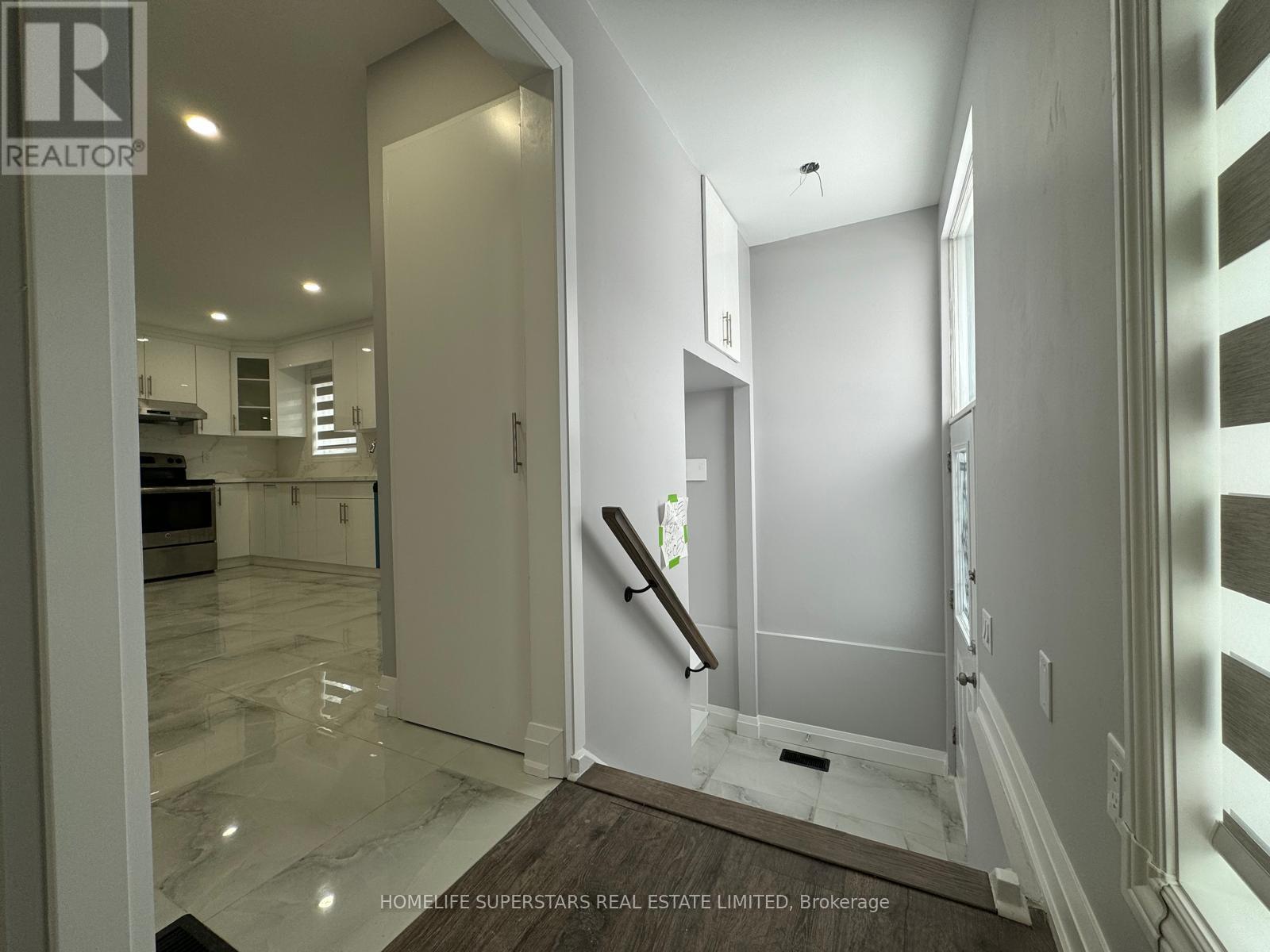 A hallway with a marble floor and white walls leading to a staircase.