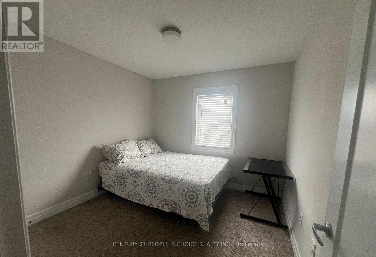 A bedroom with a bed, a small table, and a window.
