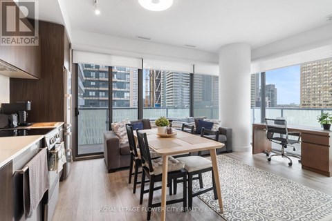 A modern kitchen with a dining table and chairs in the foreground and a view of a city skyline through the windows.