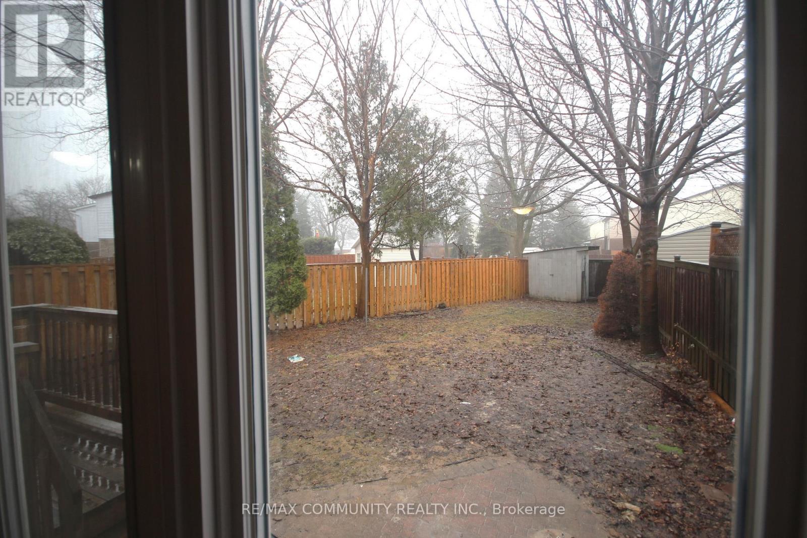 A backyard with a fence and trees visible through a window.