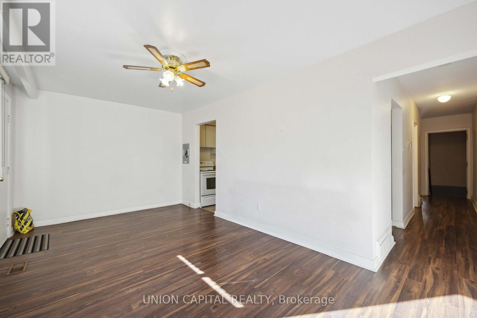 A spacious room with a ceiling fan and wooden flooring.