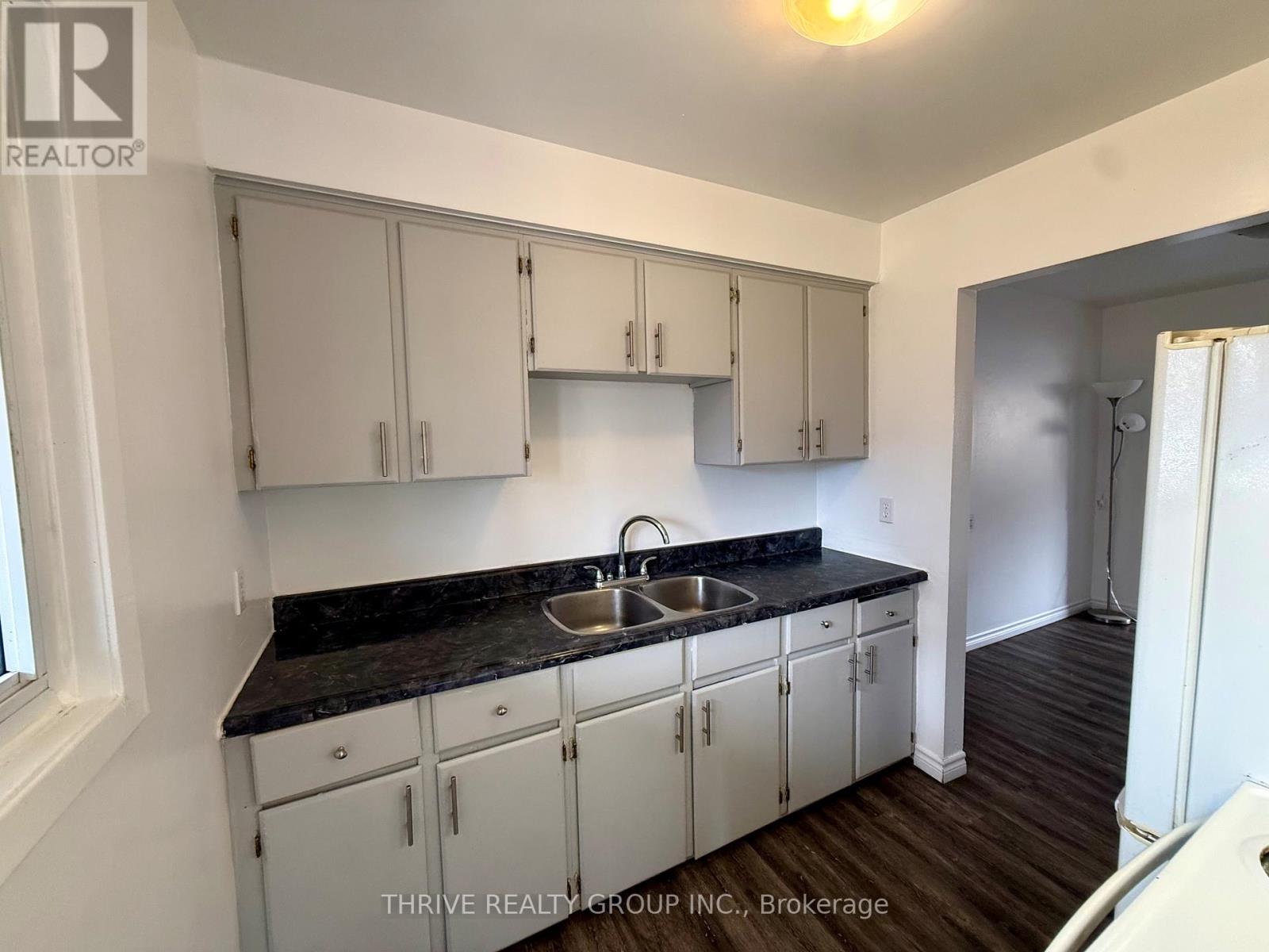A kitchen with white cabinets and a black countertop.