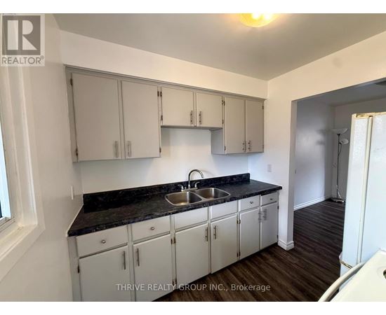 A kitchen with white cabinets and a black countertop.