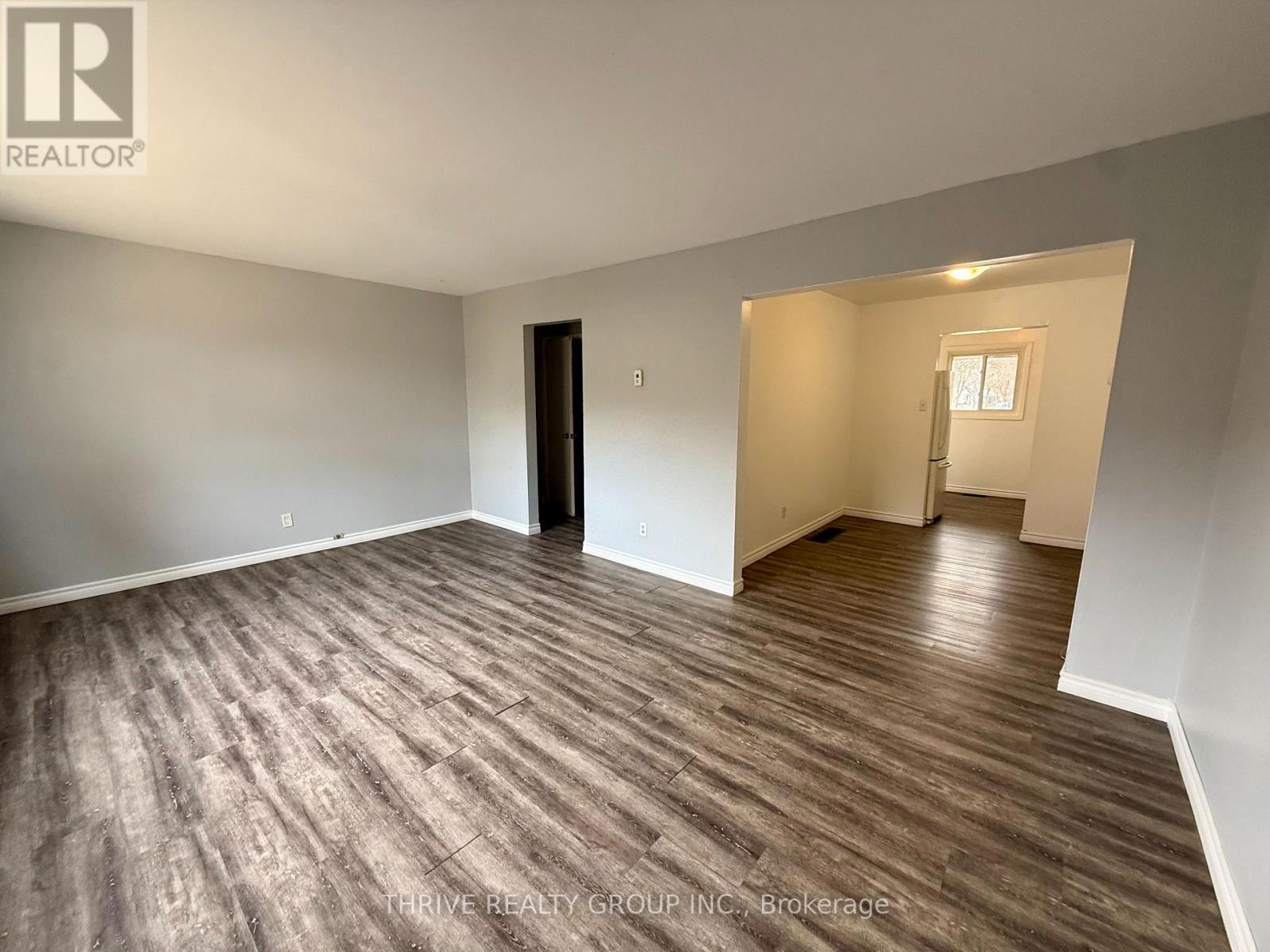 A room with wood flooring and a door on the left side.