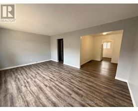 A room with wood flooring and a door on the left side.