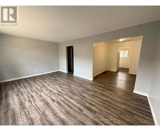 A room with wood flooring and a door on the left side.