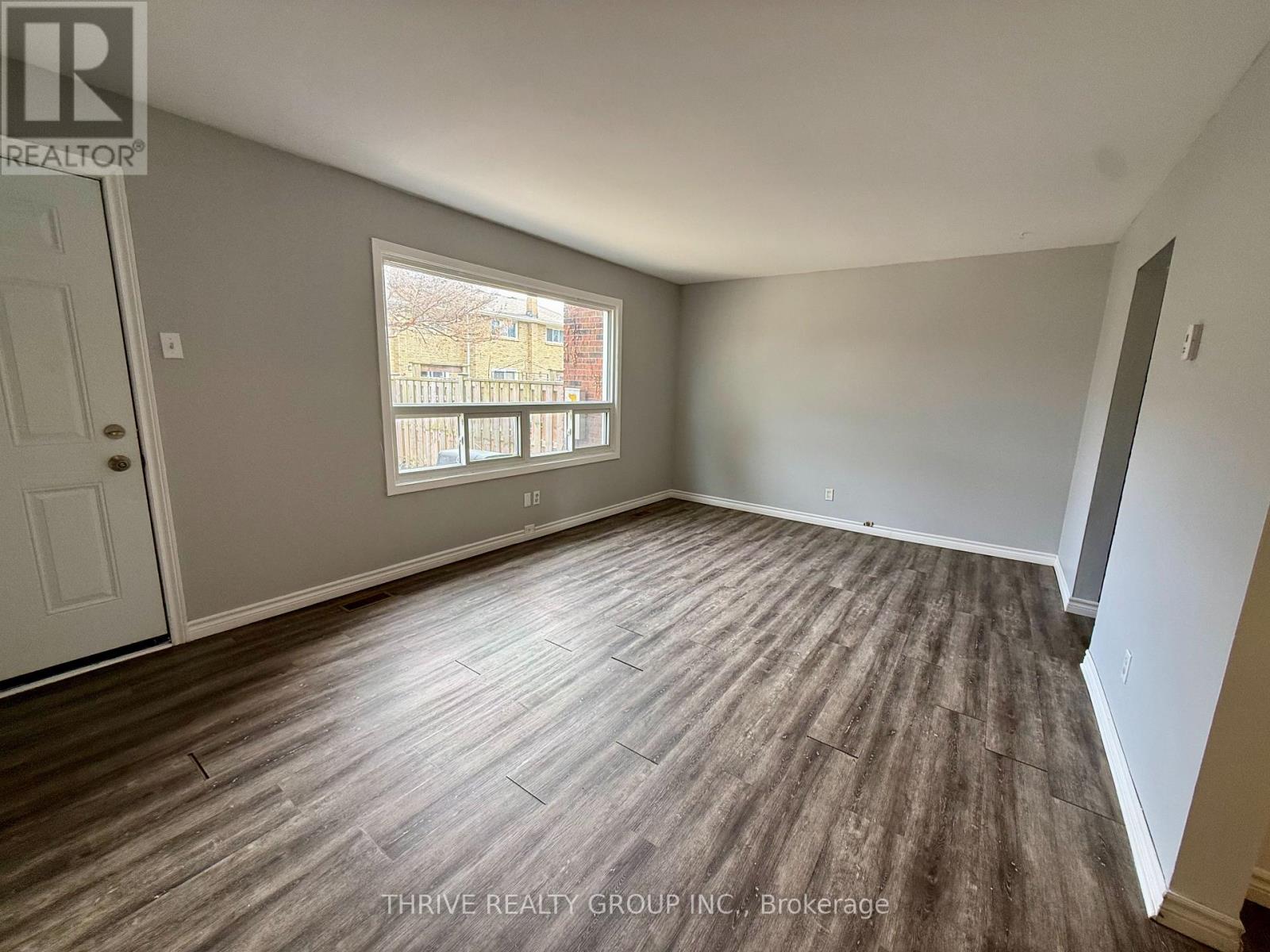 A room with wood flooring and a window overlooking a balcony.