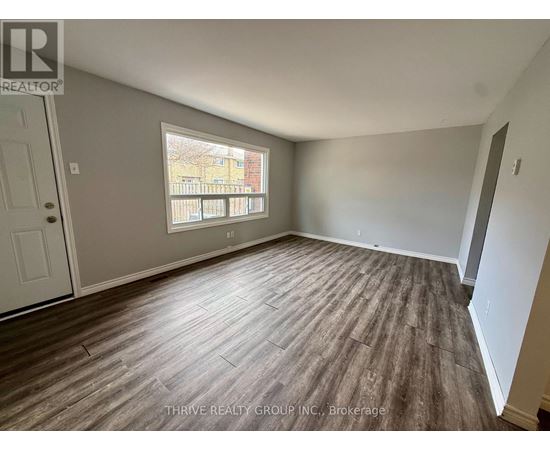 A room with wood flooring and a window overlooking a balcony.