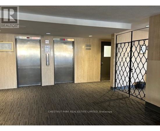 A hallway with a metal gate and wood panelled doors.