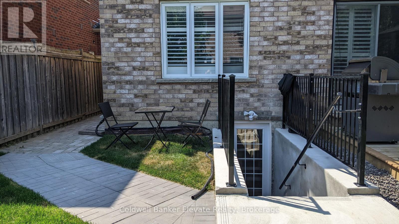 A patio with a table and chairs is in front of a brick house.
