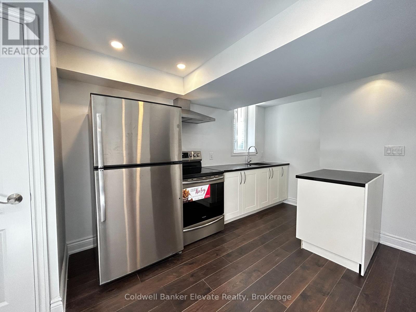 A kitchen with a stainless steel refrigerator and wooden floors.