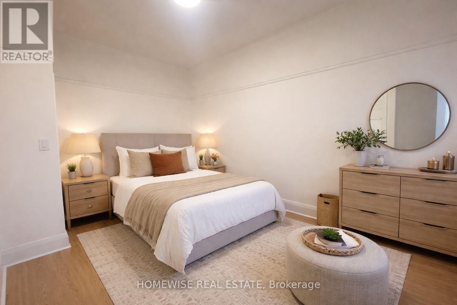 A bedroom with a bed, nightstands, and a round mirror on the wall.