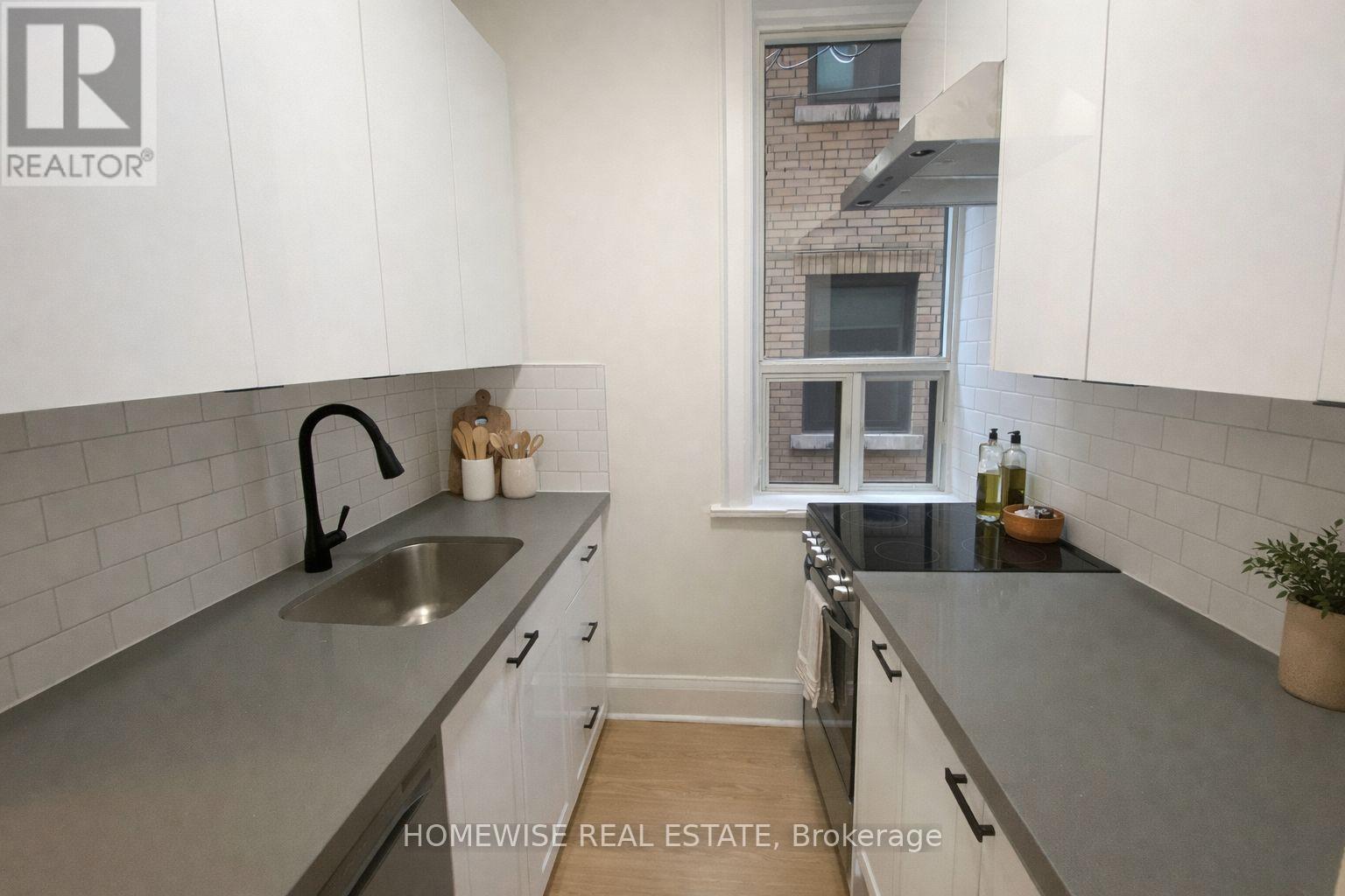 A kitchen with white cabinets and a grey countertop.