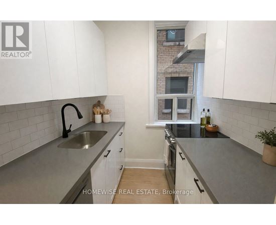 A kitchen with white cabinets and a grey countertop.