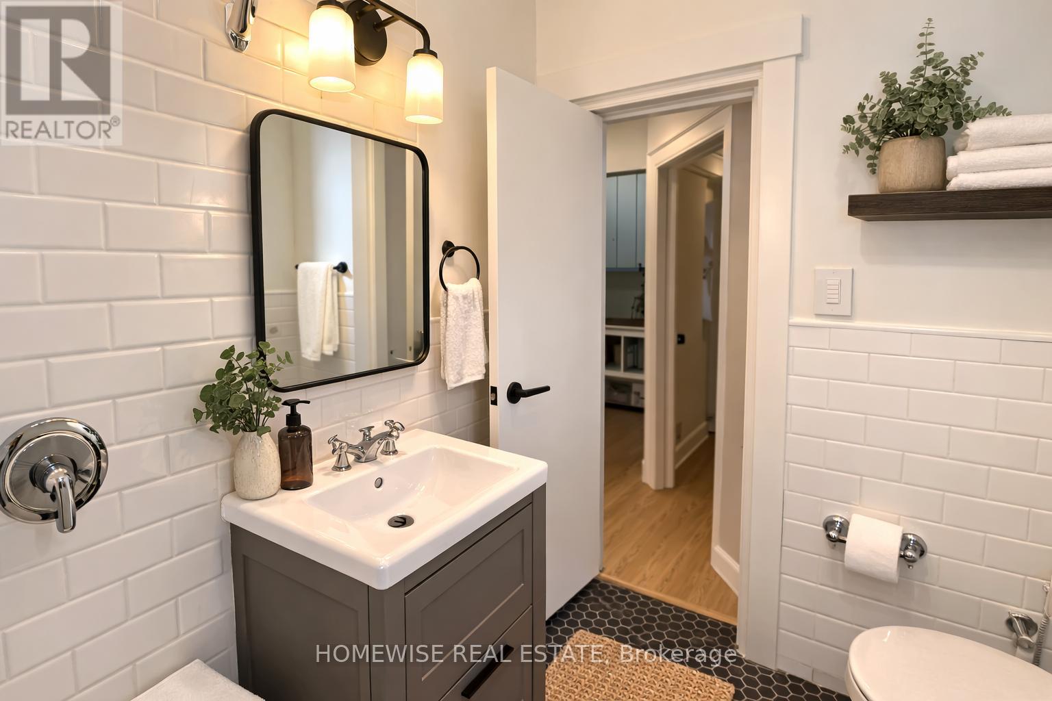 A bathroom with a sink, mirror, and toilet paper holder.
