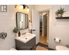A bathroom with a sink, mirror, and toilet paper holder.