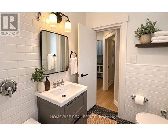A bathroom with a sink, mirror, and toilet paper holder.