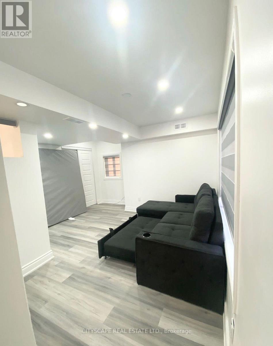 A living room with a black couch and grey carpet.