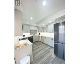A modern kitchen with a refrigerator on the right and a countertop with a white candle on it.
