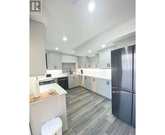 A modern kitchen with a refrigerator on the right and a countertop with a white candle on it.