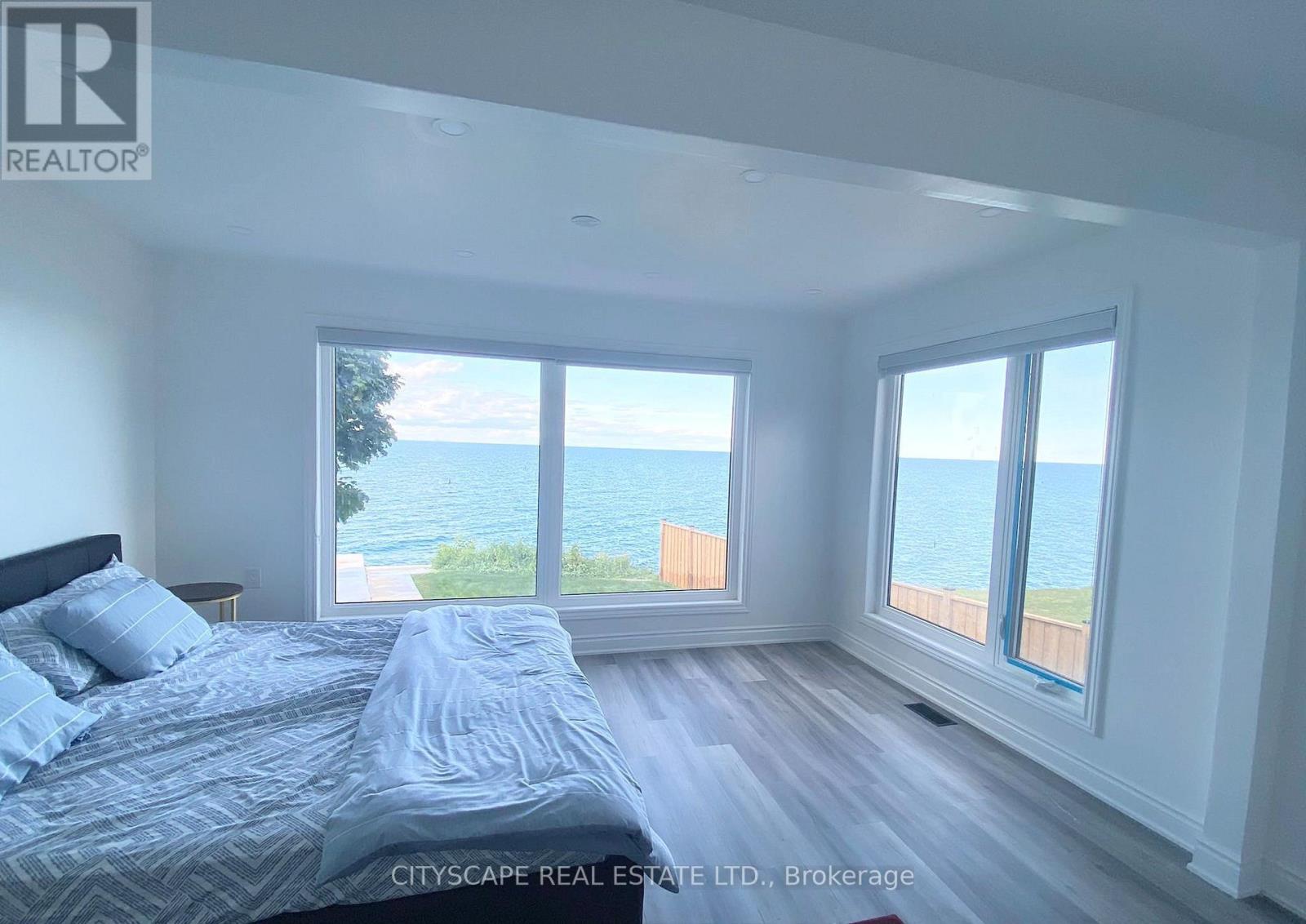A bedroom with a large bed and a view of the ocean through the windows.