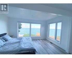 A bedroom with a large bed and a view of the ocean through the windows.