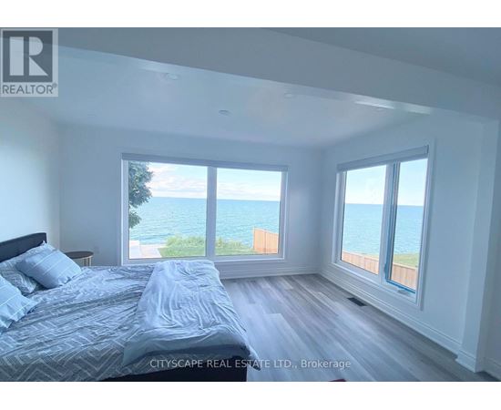 A bedroom with a large bed and a view of the ocean through the windows.