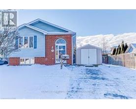 A house with a red brick facade and a white garage door is surrounded by snow.