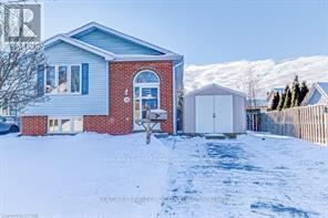 A house with a red brick facade and a white garage door is surrounded by snow.