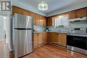A kitchen with wooden cabinets and a stainless steel refrigerator.