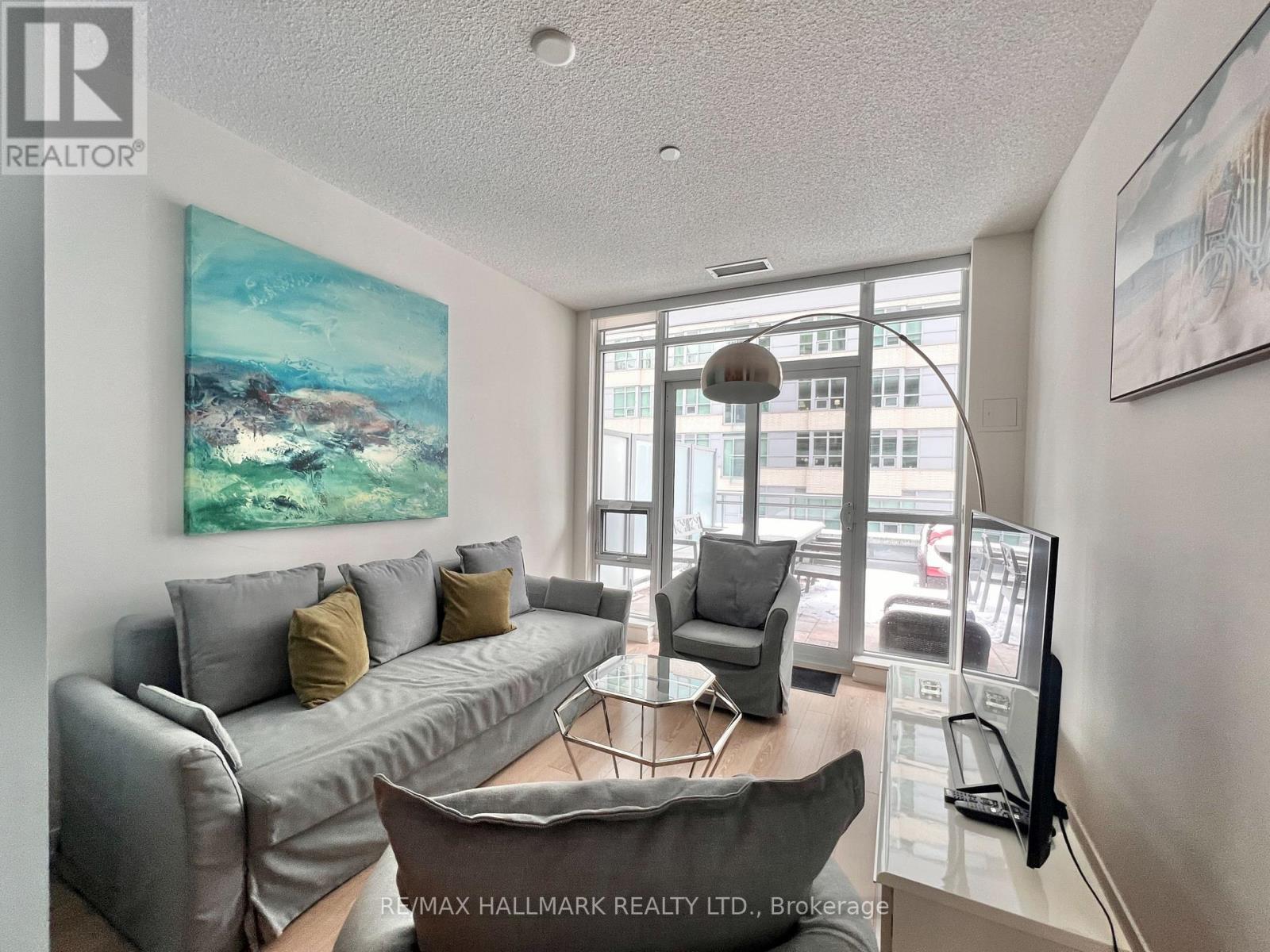 A living room with a grey couch and a painting on the wall.