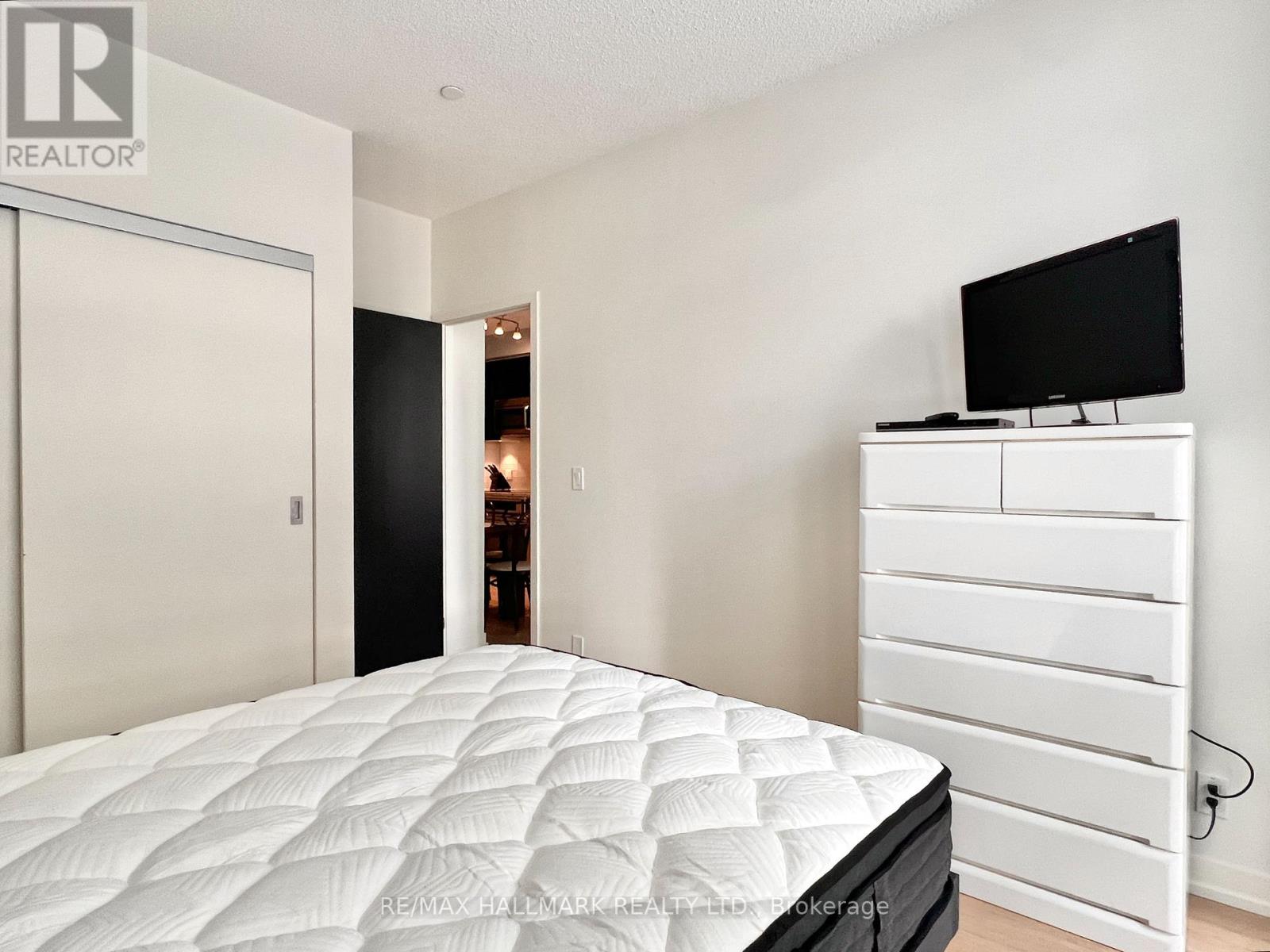 A bedroom with a white bed and a black TV.