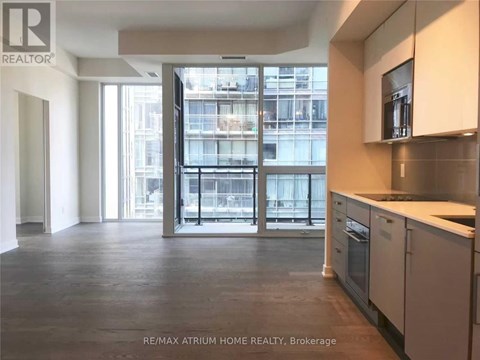 A spacious kitchen with white cabinets and a view of a cityscape through the glass doors.
