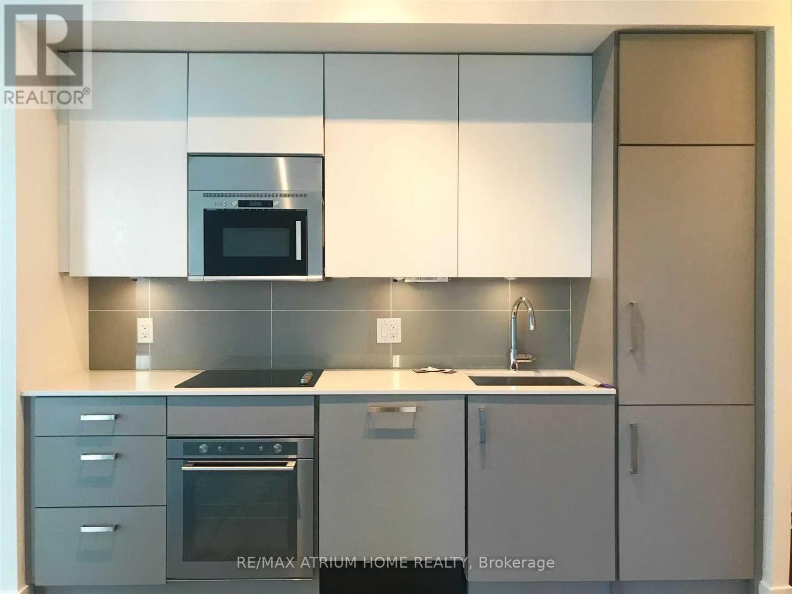 A modern kitchen with a stainless steel oven and white cabinets.