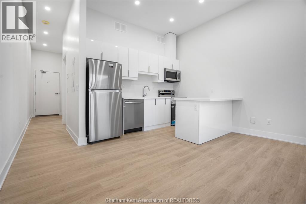 A kitchen with a refrigerator, microwave, and oven.