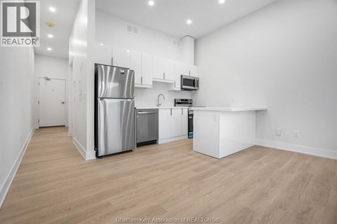 A kitchen with a refrigerator, microwave, and oven.